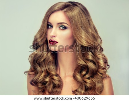Beautiful girl with long wavy hair .  fair-haired  model  with curly hairstyle   and fashionable makeup . Bright purple lips