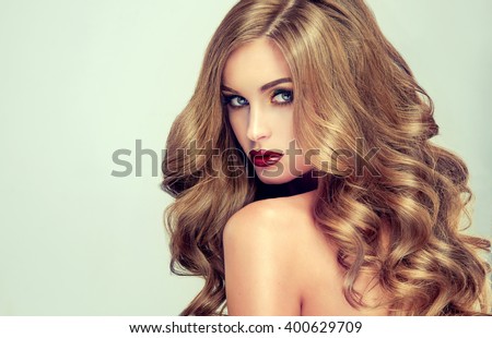 Beautiful girl with long wavy hair .  fair-haired  model  with curly hairstyle   and fashionable makeup . Bright purple lips