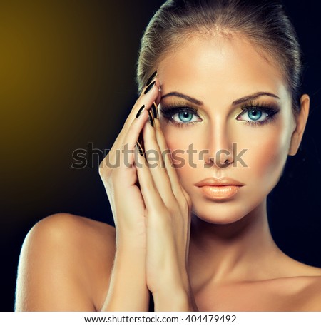 Beautiful girl with the Golden makeup and gold  metal nails.  Fashion woman Portrait