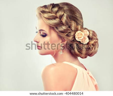 Beautiful model girl  with elegant hairstyle and rose flowers in a plait . Woman with fashion wedding hair.