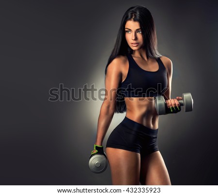 Beautiful fitness woman lifting dumbbells . Fitness sporty girl showing her well trained body . A beautiful girl body with rippling muscles from strength training .