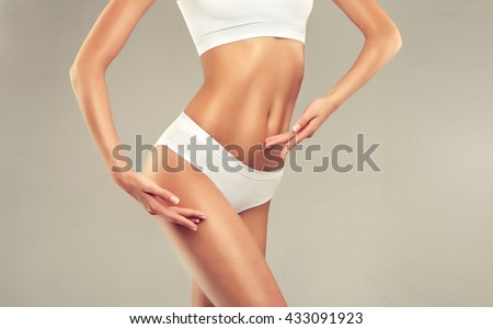 Perfect slim toned young body of the girl . An example of sports , fitness or plastic surgery and aesthetic cosmetology.