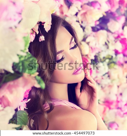 beautiful girl model with fashion  pink make-up and perfect manicure nail  near the wall   flowers . Perfume with fragrance of flowers . Perfumery and beauty .