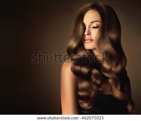 Brunette  girl with long  and   shiny wavy hair .  Beautiful  model with curly hairstyle . Head and shoulders