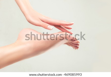Perfect clean female feet . Beautiful and elegant groomed girl\'s hand touches her feet . Spa ,scrub and foot care .