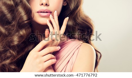 Beautiful girl  long , thick curly hair . Model showing a French manicure on nails .