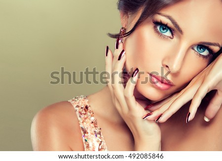 Beautiful model girl with pink metallic manicure on nails . Fashion makeup and cosmetics . Pink dress with rhinestones