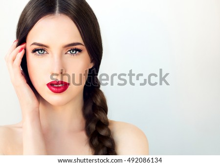 Beautiful  brunette model girl with  long braid hair . Hairstyle  pigtail  . Red lips and nails manicure .