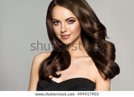 Beautiful model girl with long wavy and shiny hair . Brunette woman with curly hairstyle