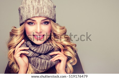 beautiful  young blonde  woman in gray wool winter hat and scarf smiling .  Portrait of beauty  winter girl  in knitted  woolen  clothing hat and  Snood .