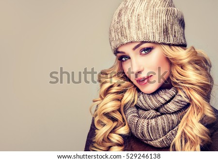 trendy warm winter - beautiful  young blonde  woman in gray wool winter hat and scarf smiling .  Portrait of beauty  winter girl  in knitted  woolen  clothing hat and scarf  Snood .