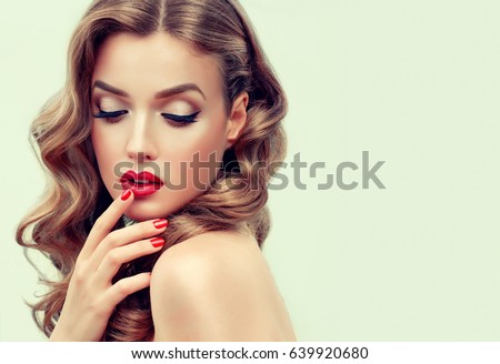 Beautiful  blonde model  girl  with long curly  hair . Hairstyle wavy curls . Red  lips and  nails manicure .    Fashion , beauty and make up portrait