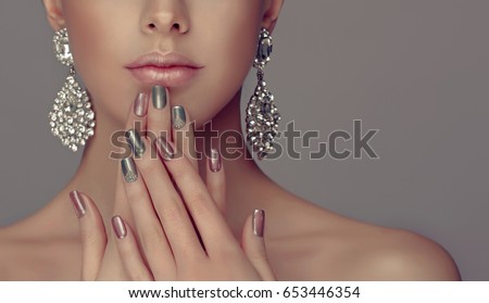 Beautiful model girl with pink and gray  silver  metallic manicure on nails . Fashion makeup and cosmetics . Big silver diamond shine  earrings jewelry .