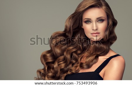 Brunette brown girl with long  and   shiny curly hair .  Beautiful  model woman  with curly hairstyle. Care and beauty