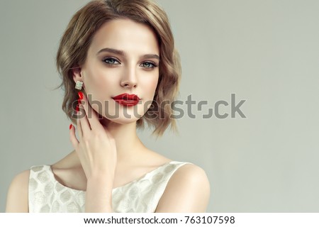 Beautiful model girl with short curly  hair and red lips . Red manicure on nails .Beauty and esthetic care