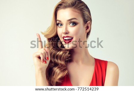 Surprised woman showing product .Beautiful girl with curly hair, pointing a finger at the top . Presenting your product. Expressive facial expressions . Teaching and edification .