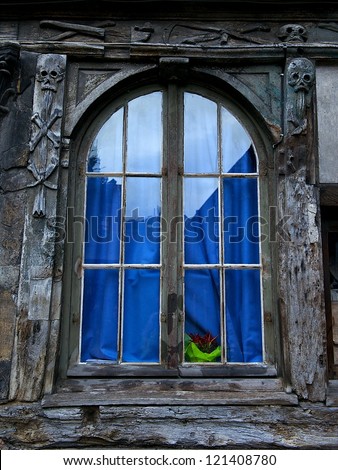 One window in french style in Normandy with blue curtain, old window, aged window, window texture, architecture details close up