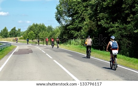 Young group riding bicycles by dirty road in countryside,group cyclists on a way between trees,young cyclists touring in Lithuania, by bicycle in Lithuania countryside, cycling bicycle on dirty road