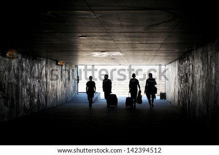 Tourists with the luggage going in the tunnel, travellers in tunnel,four people, holidays time, people on vacation, people in dark tunnel, city life, tourists in the city,traveling, 4, european people