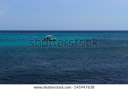 One single boat in crystal sea, Holidays in Sardinia,crystal sea and man and woman in the white boat,sardinian sea,view of beautiful sea in Sardinia,Italy.paradise, tropical island,clear sea on summer