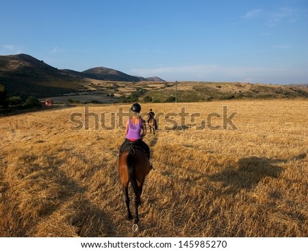 Horseback riding in the mountains at sunset,young woman and man riding a horse bareback during the gold sunset hours, horse riding in Sardinia, Sardinia landscape, Italy, horse riding, horse sport