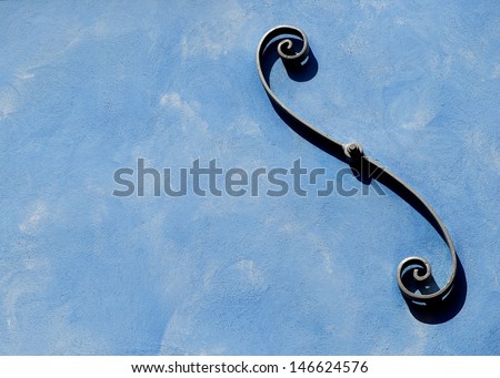 Abstract photo, metal decoration on the wall,wall decoration,exterior detail on blue dirty wall,colorfull wall with metal decoration, S form, metallic detail,blue wall fragment with the space for text