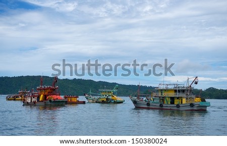 Old cargo boats in Malaysia sailing towards sunset in cloudy sky background, old and dirty fishing boats, old cargo ships in the sea, old dirty cargo ships