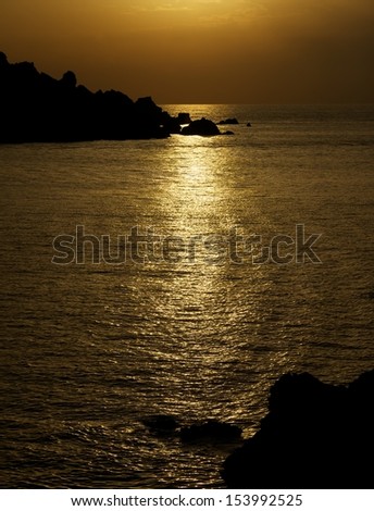Dramatic sunset with the sea, gold sky and black rock fragment, sunset scene, sea road on sunset time, calm evening