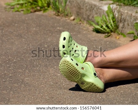 Women feet with shoes, resting woman, girls legs,woman feet on the street close up fragment, cropped, sitting woman with the flip-flops shoes in the street, selective focus on nearest part of lens