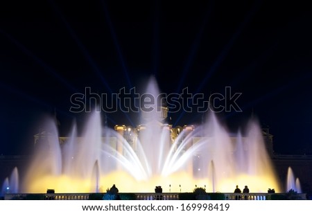 Night view of Magic Fountain light show in Barcelona, Catalonia, Spain.Magic fountain of Montjuic light show at Plaza Espanya in Barcelona with people silhouette on bottom.Blur background,illumination
