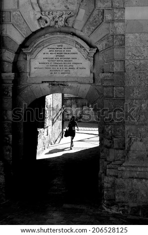 Single woman going in arch in a shadow in Birgu, Malta, Europe, loneliness, woman going , black and white contrast photo, solitude mood, solitude, street in Malta