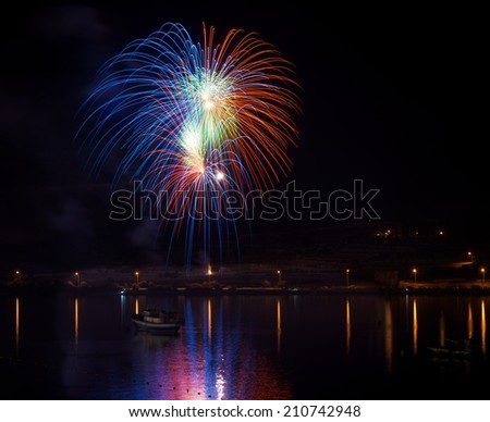 Colorful fireworks explosion in dark sky background, 4 of July, Independence day, explode, fireworks festival fragment close up with reflection in water in Malta,Malta fireworks festival, Marsaxlok