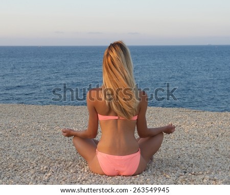 Young nice body european woman sitting meditation on a sand with the view to the sea, woman meditation in wild nature,yoga with the view to the sea, unknown girl in the beach, summer holiday