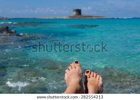 Holidays concept. woman legs in Sardinia seascape background, emerald sea in Sardinia, woman relaxing in the beach, woman leg fragment, summer holidays background