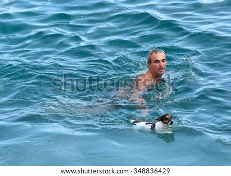 St Peter Pool Bay, MALTA-dec 8: man and dog swimming  in the water in St Peter Pool bay in Malta on Dec 8, 2015.Two crazy friends dog and man jumping to the swimming in the sea