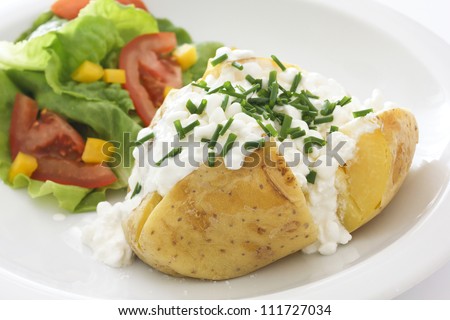 baked potato with cottage cheese, chives and fresh salad on a white plate