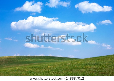 Rolling green hills and blue sky with white clouds