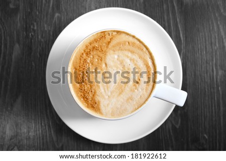 Classic foamy cappuccino in color on a black and white grained wood surface
