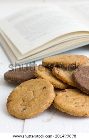 Mixed home made biscuits on white painted wood table with open book in the background.