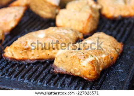 Salmon grilling on cast iron grill. Out of focus background.