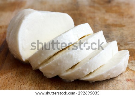 Single ball of mozzarella cheese sliced and isolated on rustic wood.