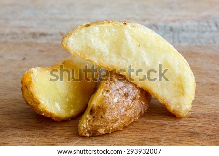 Detail of fried potato wedges isolated on rustic wood board.