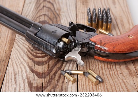 A pistol with bullets on a wooden background.