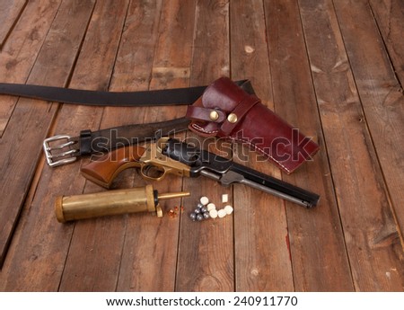 A black powder gun with holster on wood.