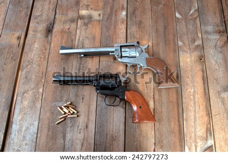 Two pistols with bullets on a wooden background.