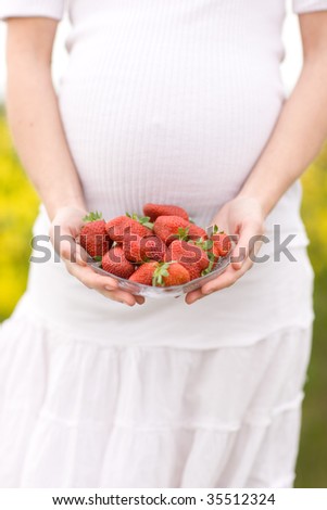 Pregnant woman holds plate of strawberry