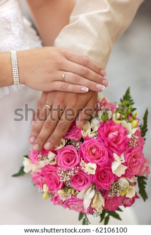 Hands of just married couple with marriage rings and bride boguet