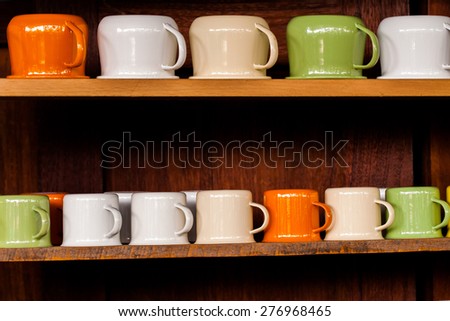 Colorful zinc cup on wooden shelves over wood background.