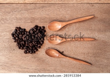 Coffee beans and bamboo spoon on wooden background.