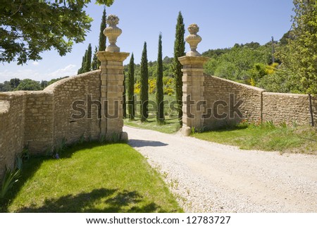 A stone gateway and a long driveway lined with cedar trees.